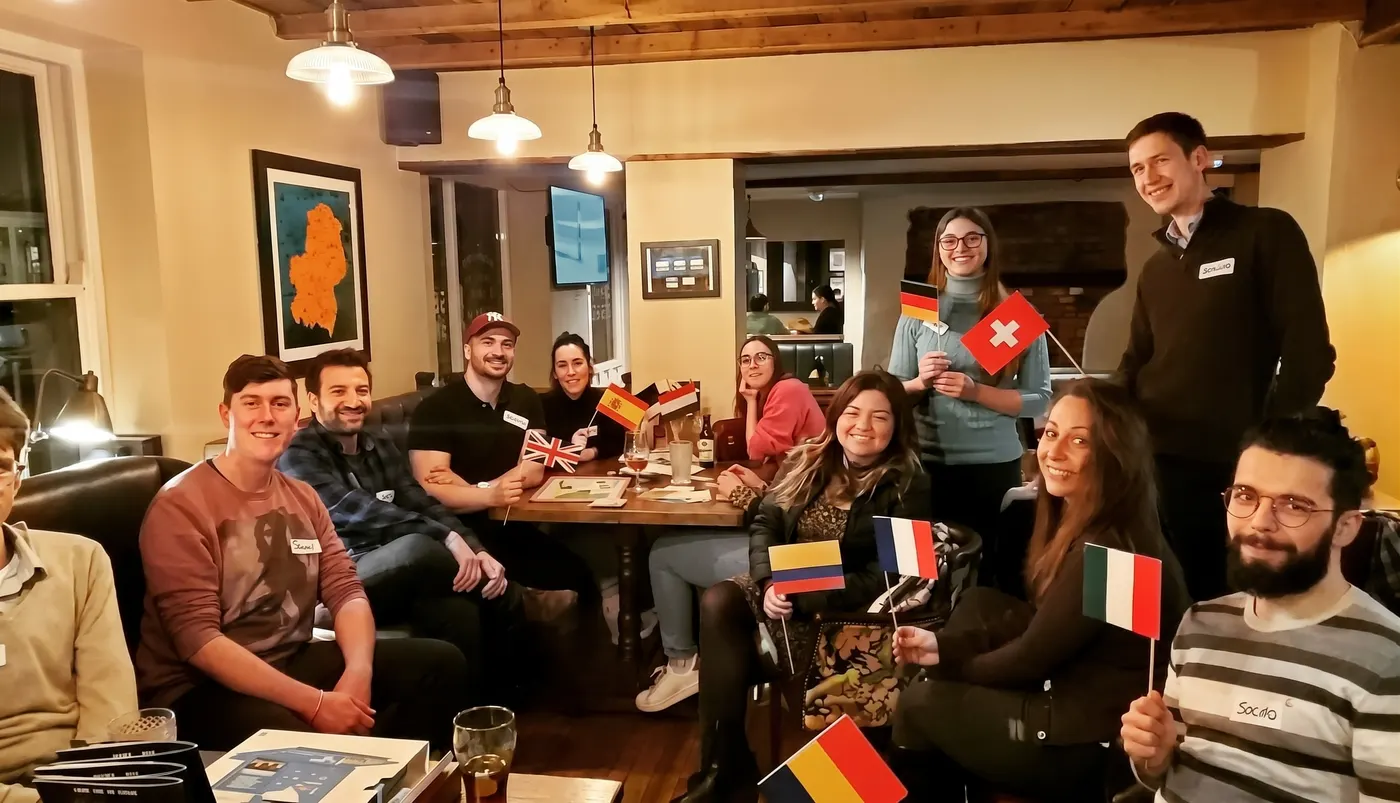 A Guildford Babel evening: a group around a pub table, holding flags of the languages they speak