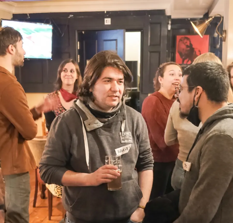Members talking in small groups, drinks in hand, at a Guildford Babel evening